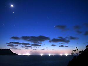 イカ釣り漁船の漁火と日本海の月夜の夜景と星空