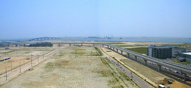 神戸空港・空港島と神戸スカイブリッジ（神戸空港連絡橋）/手前はポートアイランド第２期埋立地とポートライナー延伸工事