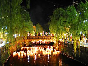 大谿川をゆっくりと流れる竹灯籠と城崎の夜景